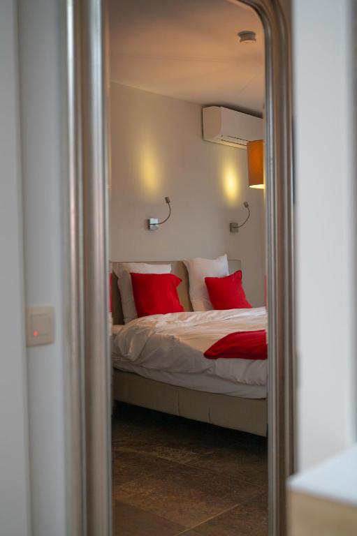 波佩林赫安菲拉宾馆的一间卧室配有一张带红色枕头和镜子的床