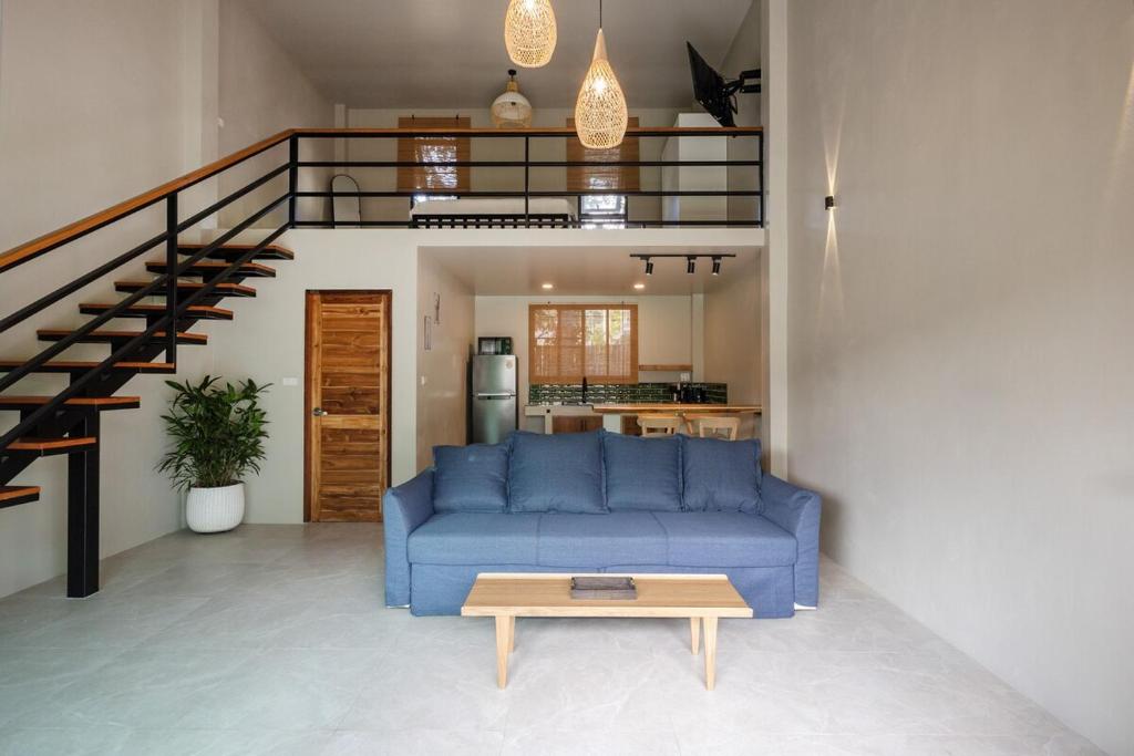 een woonkamer met een blauwe bank en een tafel bij Aqua Luxe in Srithanu