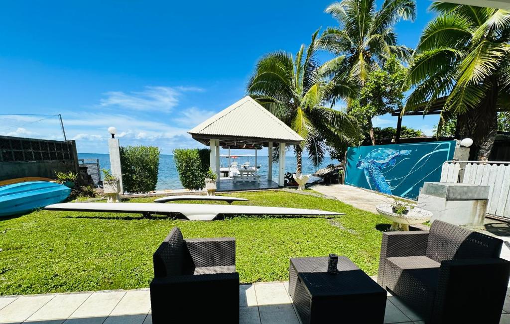 een achtertuin met een prieel, palmbomen en uitzicht op de oceaan bij Okilei House in Taputapuapea