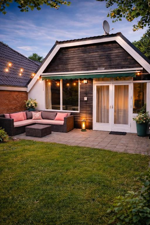 a house with a patio with pink couches in a yard at 3 bedrooms Family House till 6 p Near Amsterdam & Sea in Opmeer