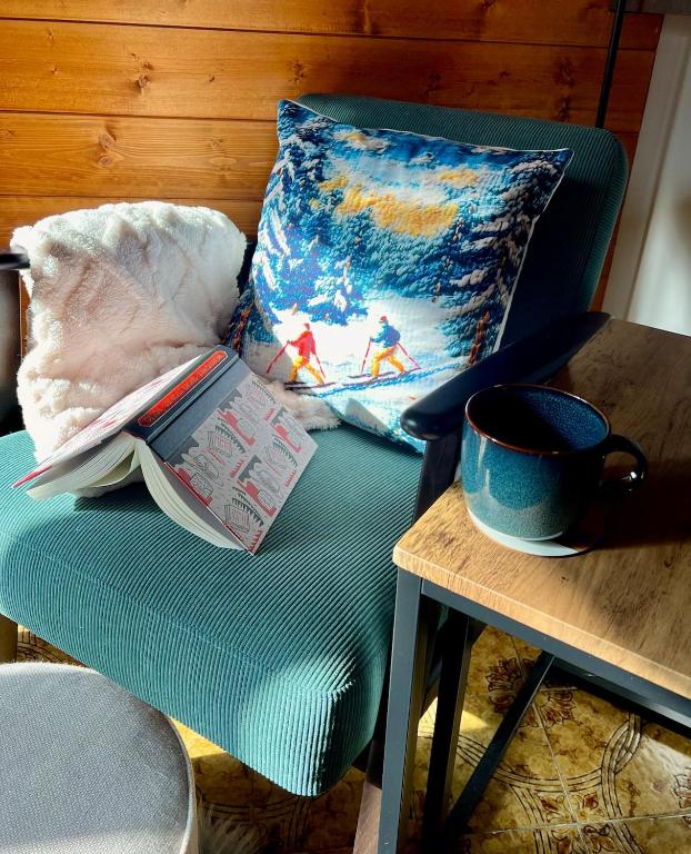a blue chair with a book and a cup of coffee on a table at The Mountain Escape - Luxury Apartment in Prato Nevoso
