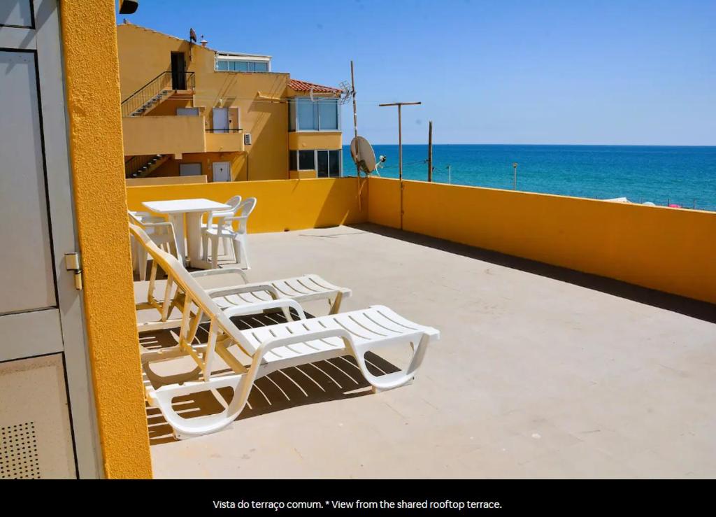a balcony with chairs and a table and the ocean at Blife Mariangya private rooms at Faro beach in Faro