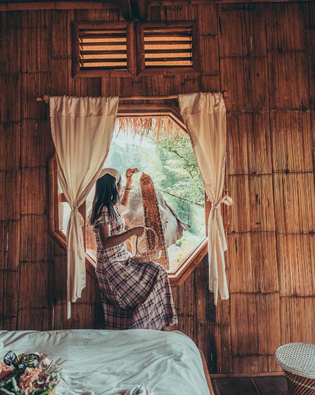 a woman looking out the window of a room at Lazy mango homestay in Ban Mae Sapok Nua