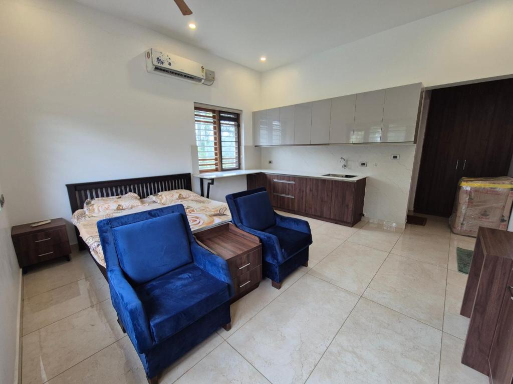 a bedroom with a bed and two blue chairs at Prabhu Villla Upper Deck in Perumpāvūr
