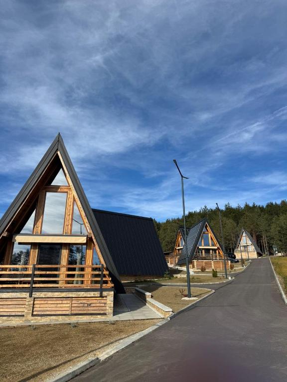 a wooden house with a gambrel roof on a street at Vodice Park, Zlatibor in Vodice