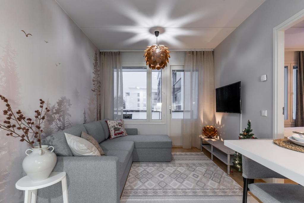 a living room with a gray couch and a tv at Scandi Forest Flat Across from the Train Station in Rovaniemi