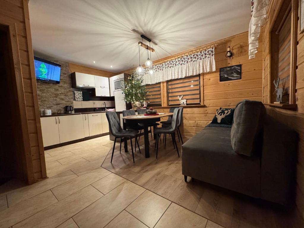ein Wohnzimmer mit einer Couch und einem Tisch mit Stühlen in der Unterkunft Domek Przy Potoku in Murzasichle