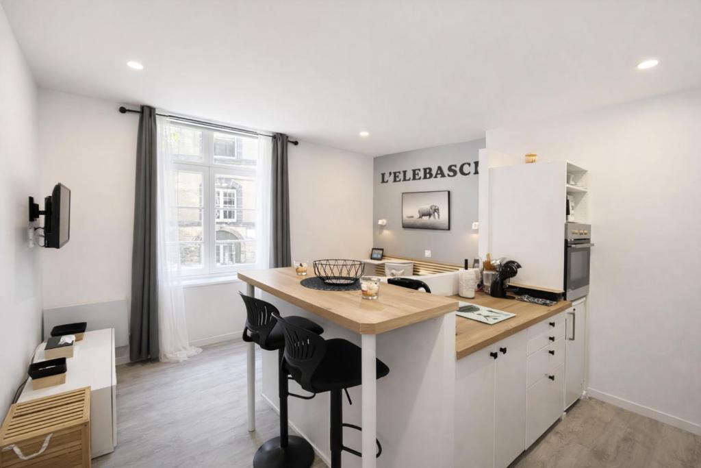 eine Küche mit weißen Schränken und einer Holzarbeitsplatte in der Unterkunft L'ELEBASCH - Riom - Randonnée Puy de Dôme in Riom