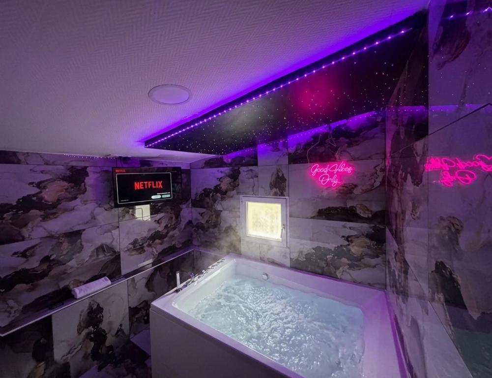 een badkamer met een bad met een klok aan de muur bij Maison avec jacuzzi in Villeurbanne