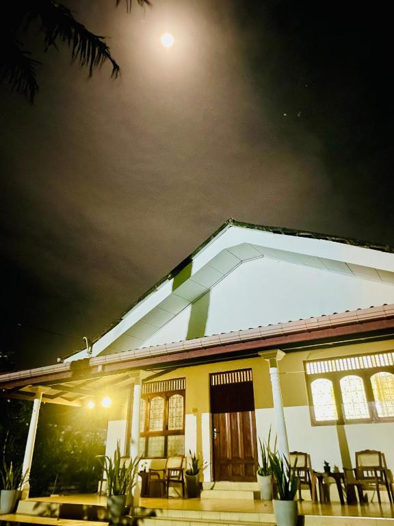 a yellow house with chairs in front of it at night at Villa 277 - Mirissa in Bandaramulla