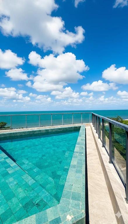a swimming pool with the ocean in the background at Beira Mar - Melhor Localização Bessa Five in João Pessoa
