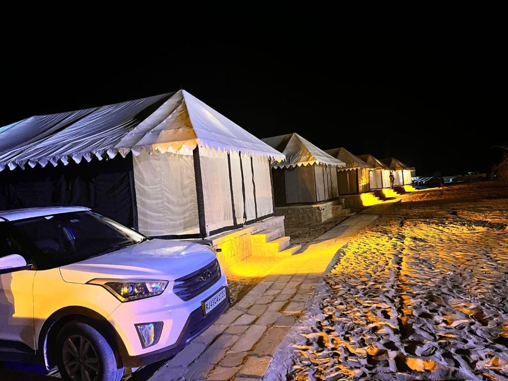 Ein weißer Geländewagen parkte vor einer Zeltreihe. in der Unterkunft Taj heritage camp& resort in Jaisalmer