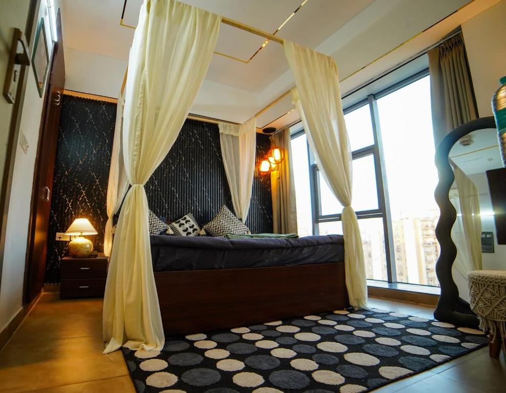 a bedroom with a canopy bed with a large window at Lux 1bhk with balcony in Noida