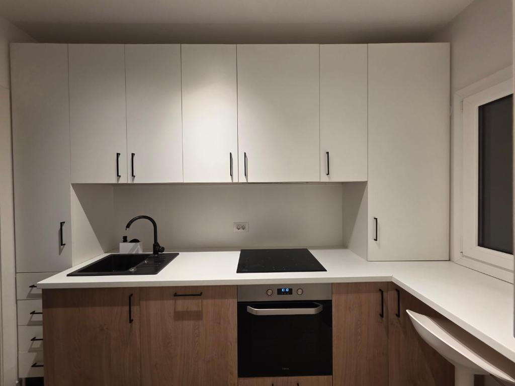 una cucina con armadi bianchi e un lavandino nero di Afi City - București Noi a Bucarest