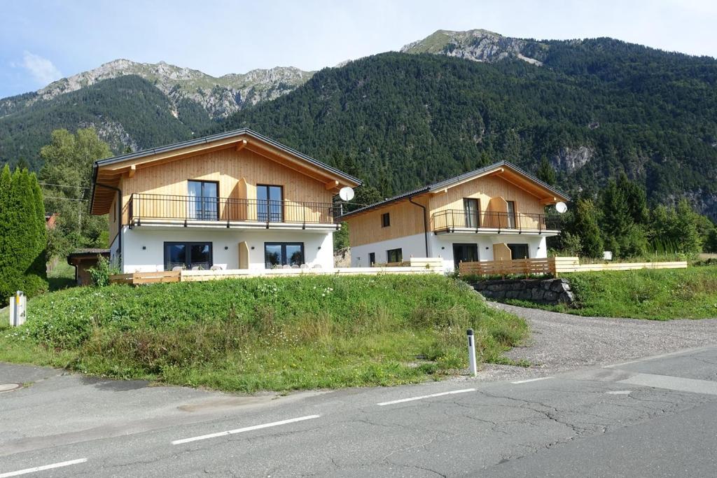 a house on a hill with mountains in the background at Chalets Dualhaus, 2 Apartments mit Sauna, Nähe Pressegger See, Skibus zum Nassfeld in Hermagor
