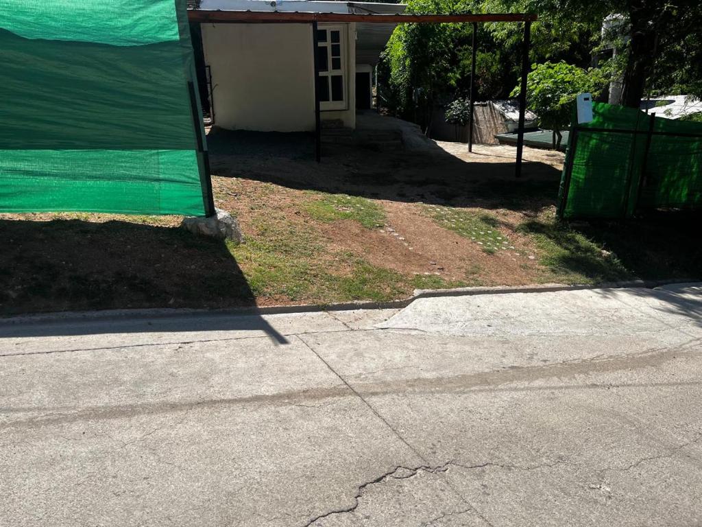 een huis met een groene overkapping aan de zijkant van een straat bij Habitaciones Monarcas in Villa Carlos Paz