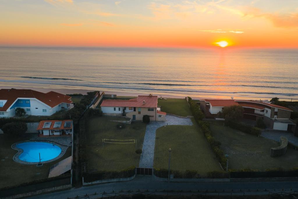 een zonsondergang boven de oceaan met huizen en een zwembad bij Dunéa - Oceanfront Luxury and Serenity - Ofir in Esposende