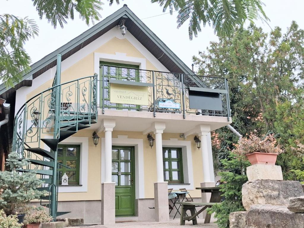 een huis met een balkon en een trap bij Vagabund Vendégház in Etyek