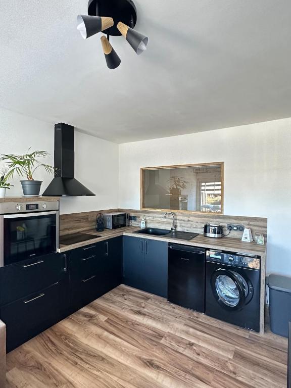 - une cuisine avec des placards noirs et un évier dans l'établissement Le Nid des Pistes, à Métabief