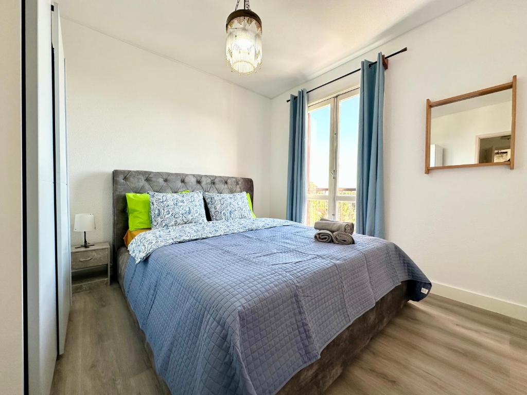 a bedroom with a bed with a blue comforter and a window at Santa Luzia Resident sea view in Funchal