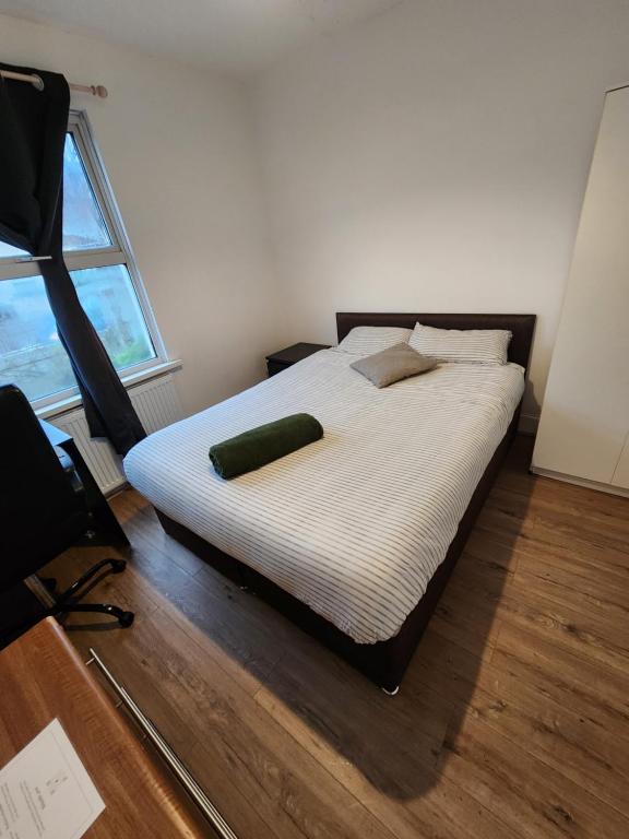 een slaapkamer met een bed met een groen kussen erop bij The Oaks in Grays Thurrock