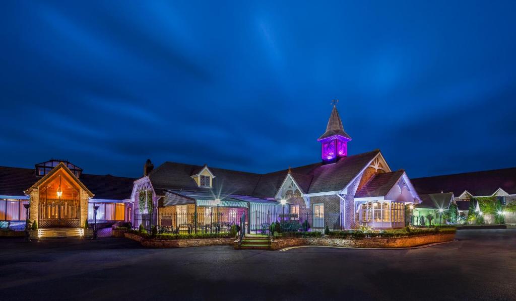 a large house with a church at night at Treacys Oakwood Hotel in Shannon