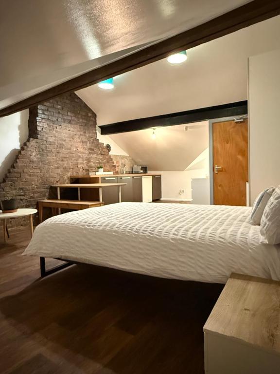 une chambre avec un grand lit et un mur de briques dans l'établissement 63 Spellow Lane, à Liverpool