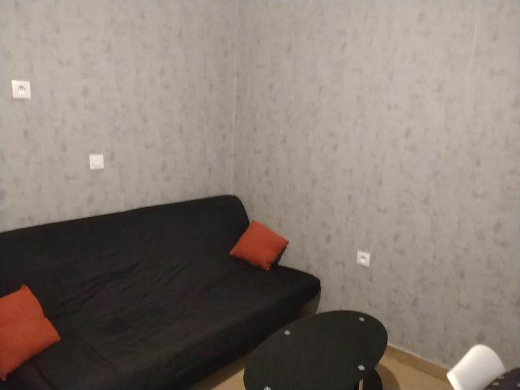 ein kleines Schlafzimmer mit einem schwarzen Bett und orangefarbenen Kissen in der Unterkunft Le repos beaurepairien in Beaurepaire