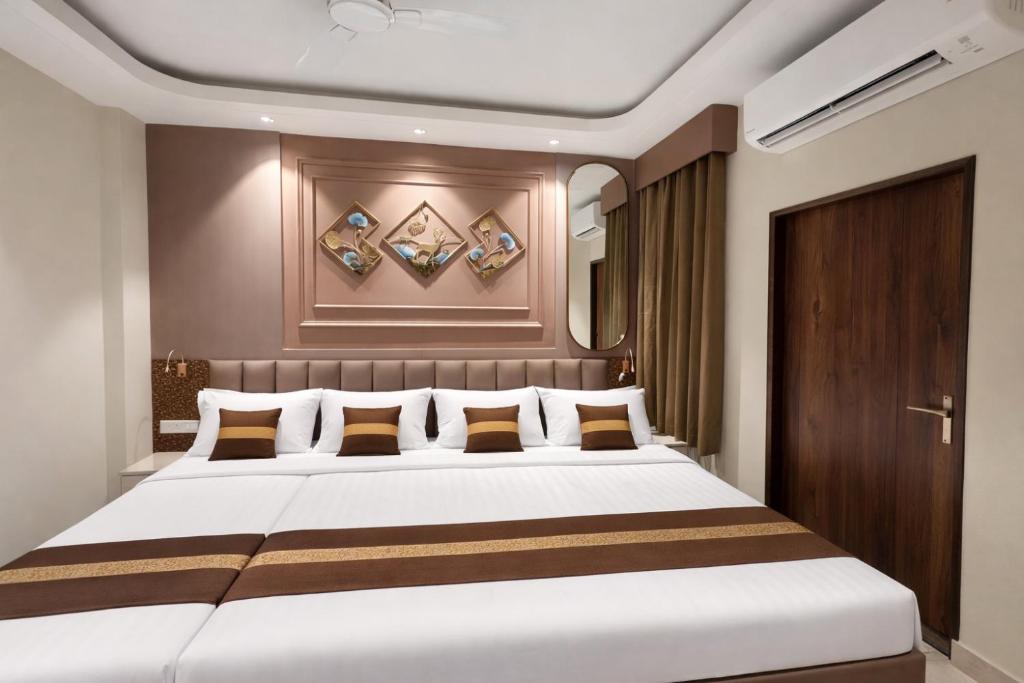 een slaapkamer met een groot wit bed met bruine kussens bij Ocean Regency in Ujjain