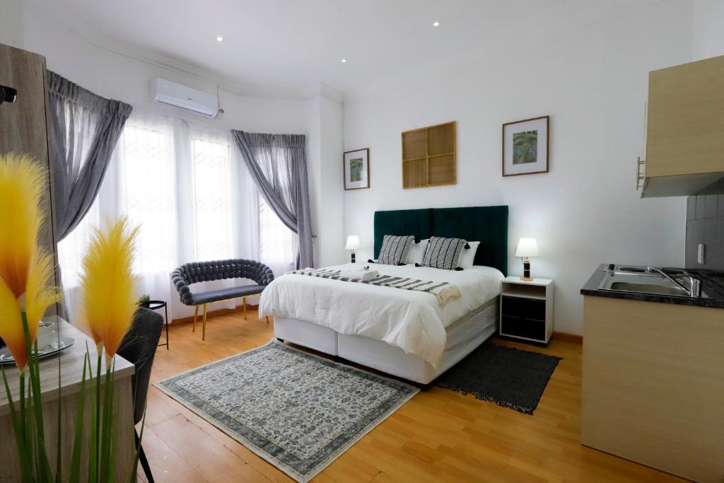 a white bedroom with a bed and a kitchen at Riveria Guest Lodge and SPA in East London