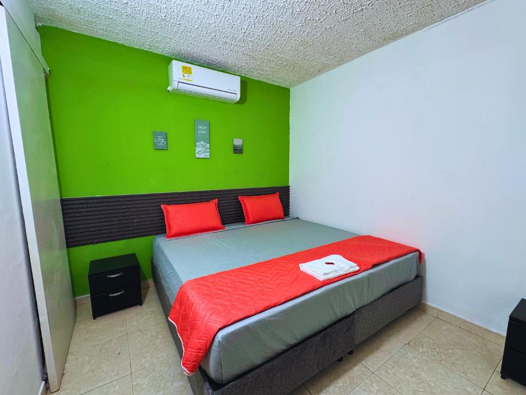 een slaapkamer met een bed met rode kussens en een groene muur bij Hotel Casa Manzanares in Santa Marta