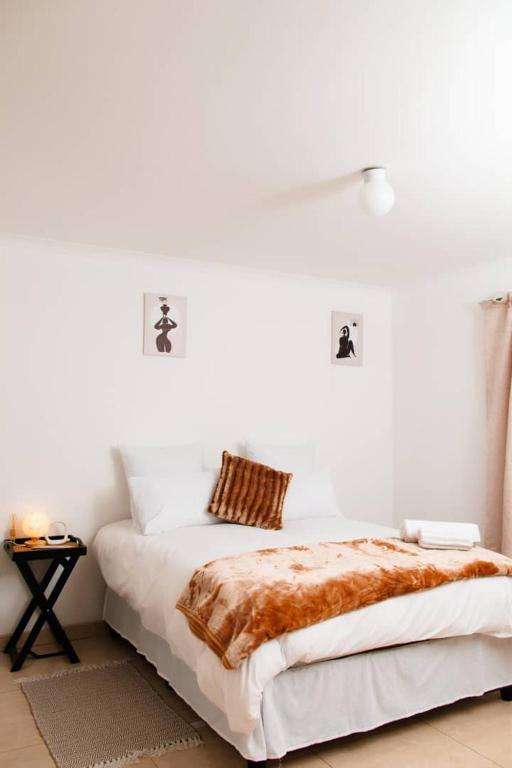 a white bedroom with a bed and a side table at Tasha Coastal Accommodation in Walvis Bay