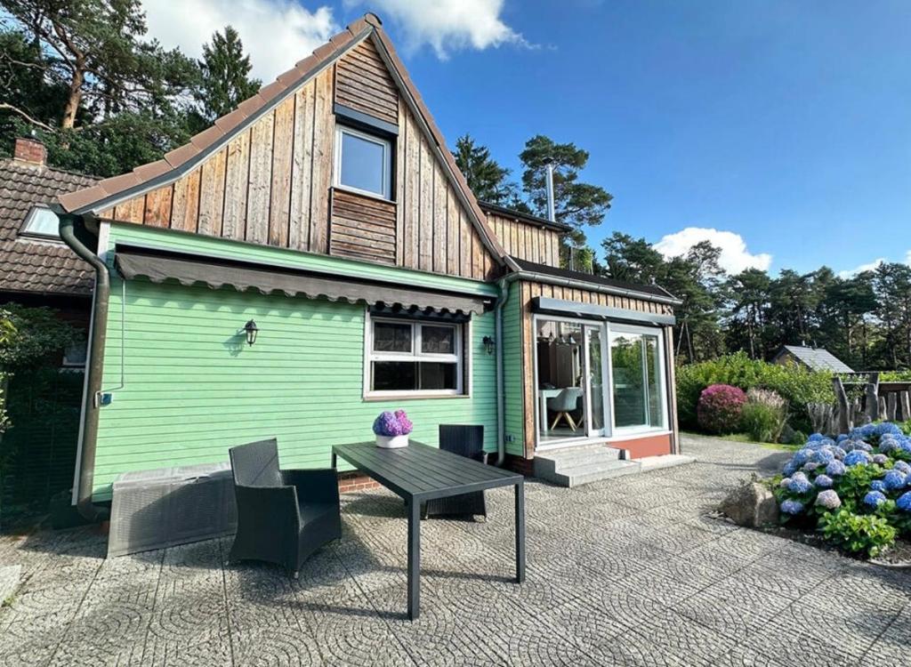 ein grünes Haus mit einem Tisch davor in der Unterkunft Waldgeflüster in Buchholz in der Nordheide