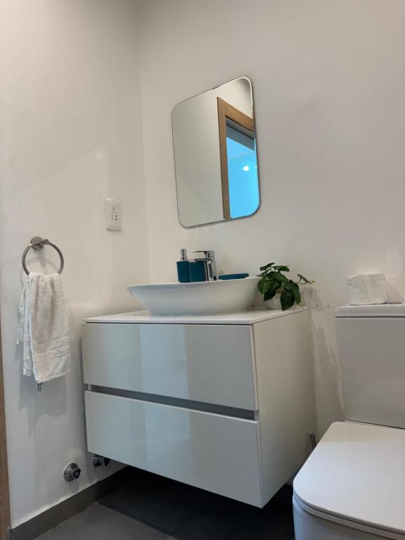 een witte badkamer met een wastafel en een spiegel bij Nova by Devtraco plus in Accra