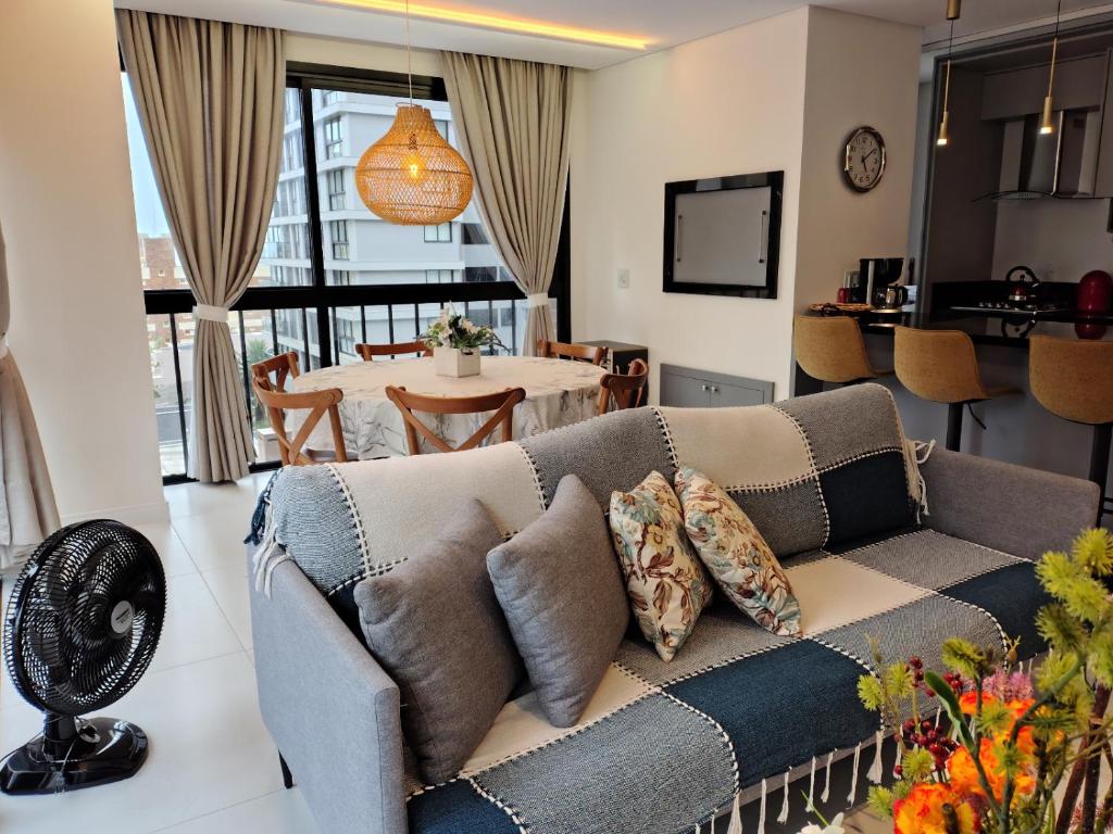 een woonkamer met een bank en een tafel bij Sinta se em casa, mas, com sol e mar in Torres