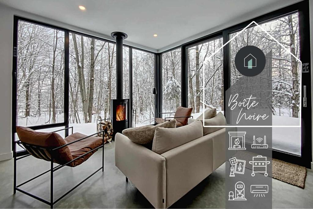 un soggiorno con divano, sedie e finestre di Chalet Black Box a Mansonville