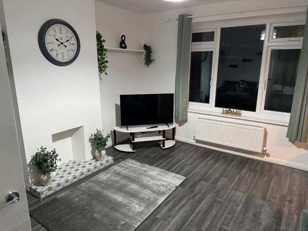 un salon avec une télévision et une horloge murale dans l'établissement Rowe Terrace Workington, à Workington