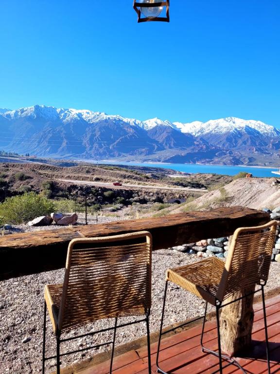 two chairs sitting on a deck with mountains in the background at RevolucionArte Potrerillos in Ciudad Lujan de Cuyo