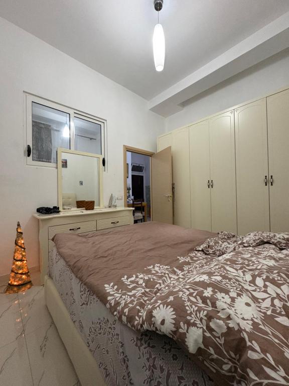 a bedroom with a bed with a dresser and a mirror at Lisi apartment in Tirana