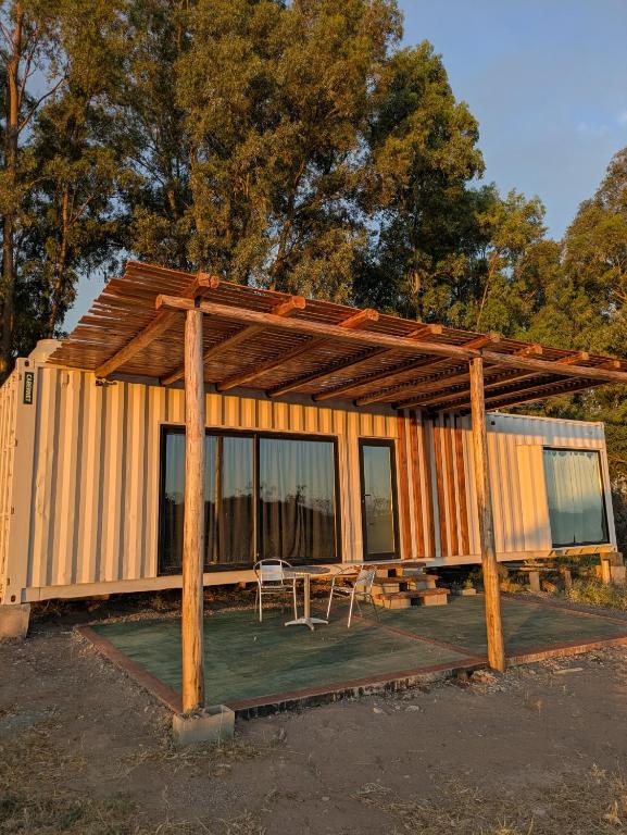 a house with a wooden roof and a table and chairs at Cabaña Container en Viñedos in San Rafael