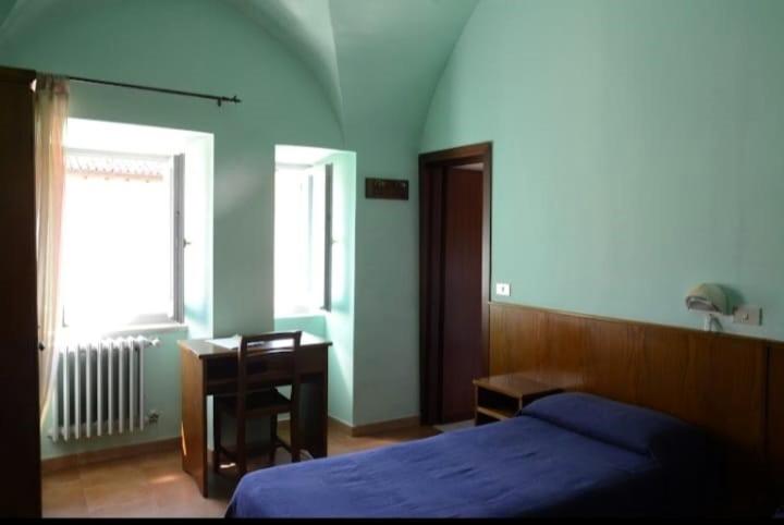 een slaapkamer met een bed, een bureau en een raam bij Oasi Francescana il Monastero in Vicovaro