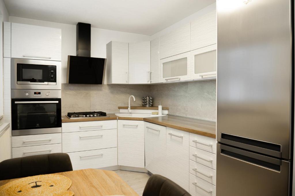 a kitchen with white cabinets and a wooden table at Apartment with Private Garden in Liptovský Mikuláš
