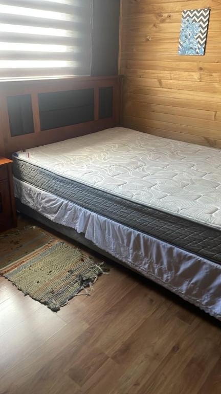 a bed in a room with a wooden floor at Departamento cómodo full equipado in Puerto Montt
