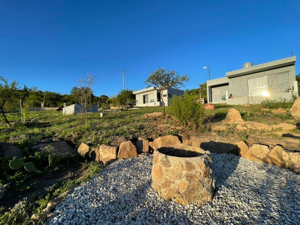 een tuin met rotsen en een huis op de achtergrond bij Entre Sierras Cabañas in Tanti