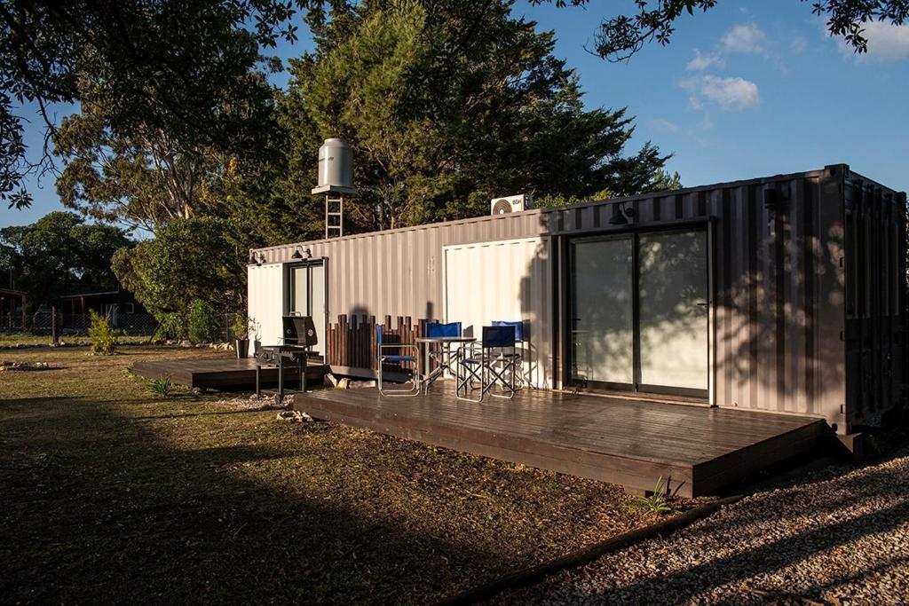 a small shed with a deck and chairs on it at Container Los Lobos in Chapadmalal