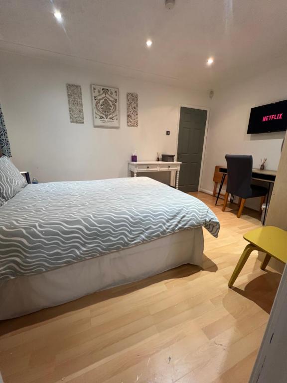 a bedroom with a bed and a desk and a chair at The Bungalow by SJP - Double Room in Northamtonshire