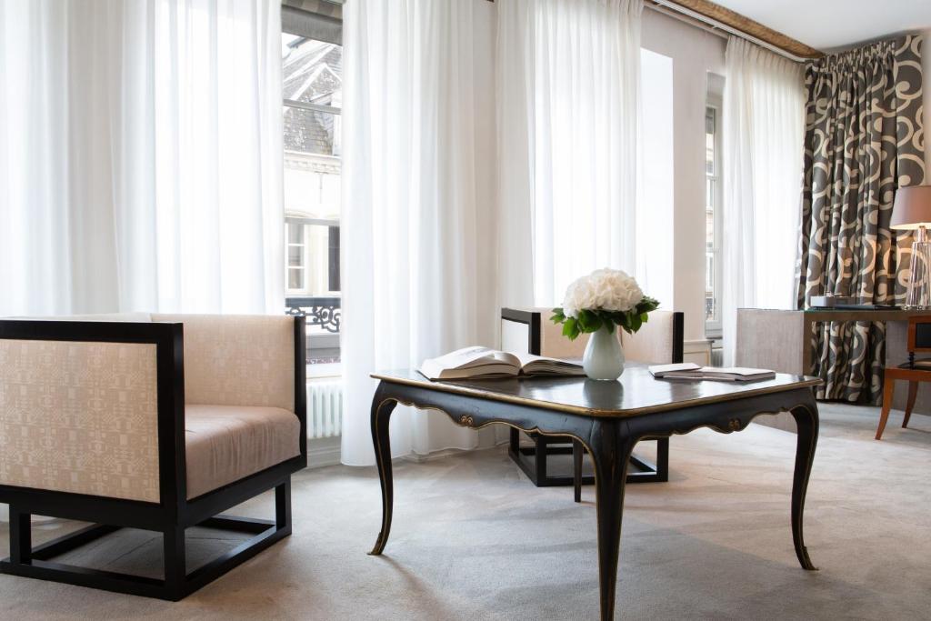 a living room with a table and a chair at Hotel Le Place d'Armes - Relais & Châteaux in Luxembourg