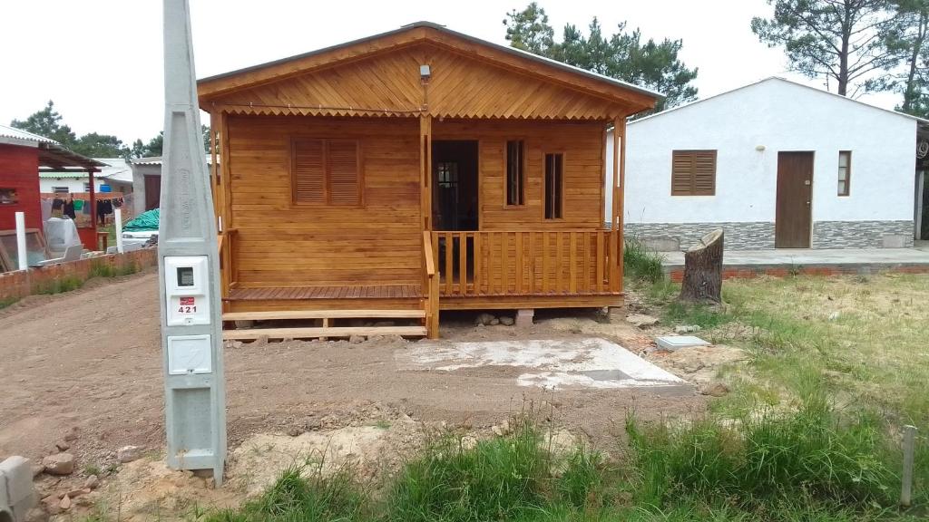 a wooden house with a porch in a yard at Cabaña Las Abuelas in Xuí