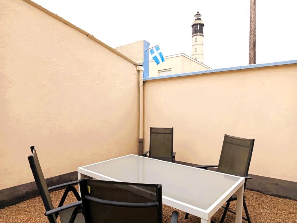 a white table and chairs on a balcony with a lighthouse at The Calais Beacon in Calais
