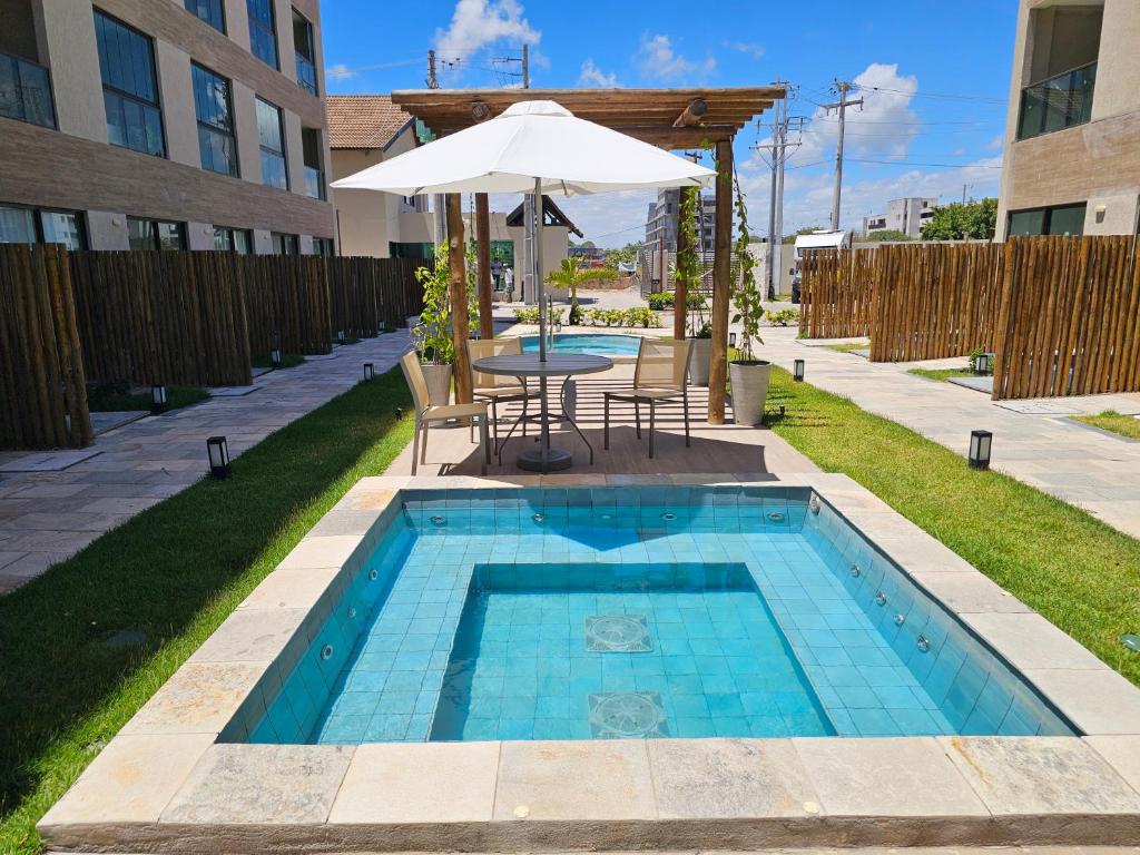 een zwembad met een tafel en een parasol bij Max Carneiros Suítes - Com e sem piscina privativa in Praia dos Carneiros
